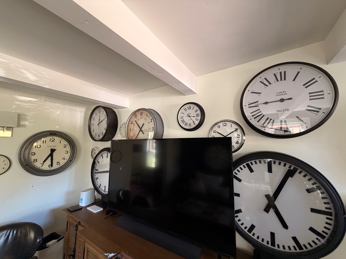 A wall of vintage station clocks around the television