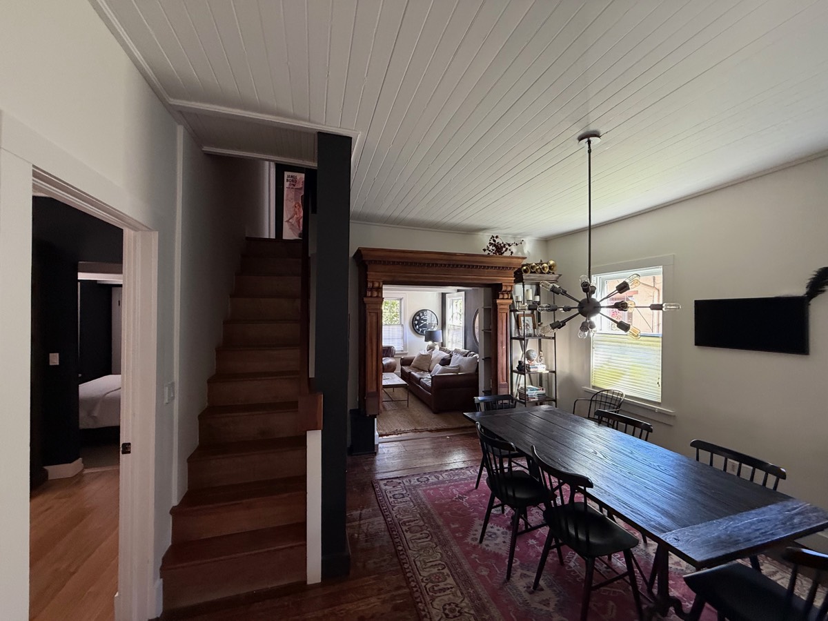 Dining room with a sputnik chandelier, the staircase to the second floor and the living room beyond