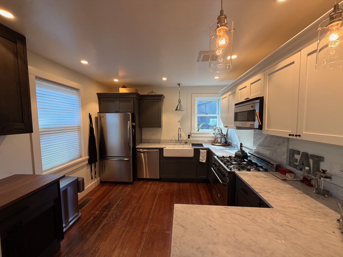 Kitchen with marble countertops, a farmhouse sink, a professional gas range and pendant lights