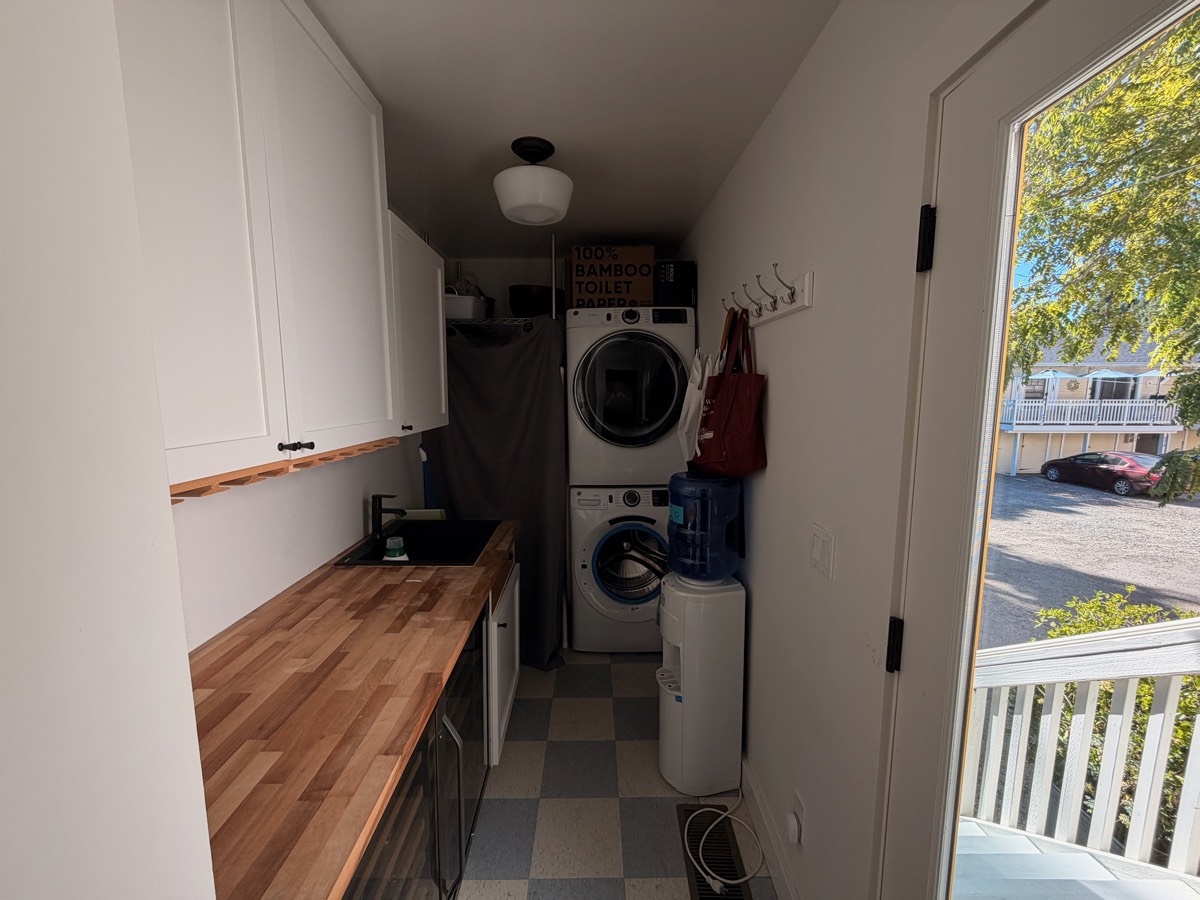 Laundry room with a stacked washer and dryer, butcher-block counter and sink
