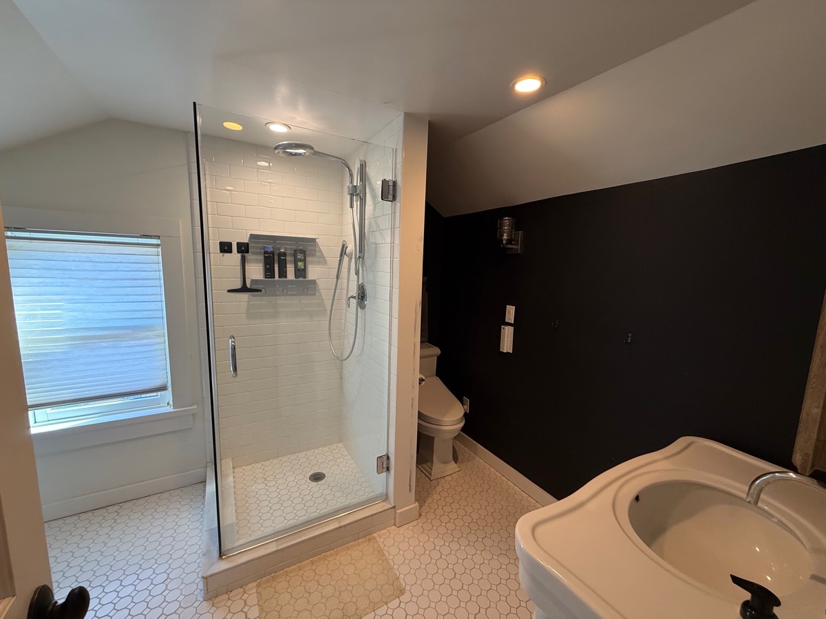 Upstairs bathroom with a glass walk-in shower, white subway tile and a pedestal sink