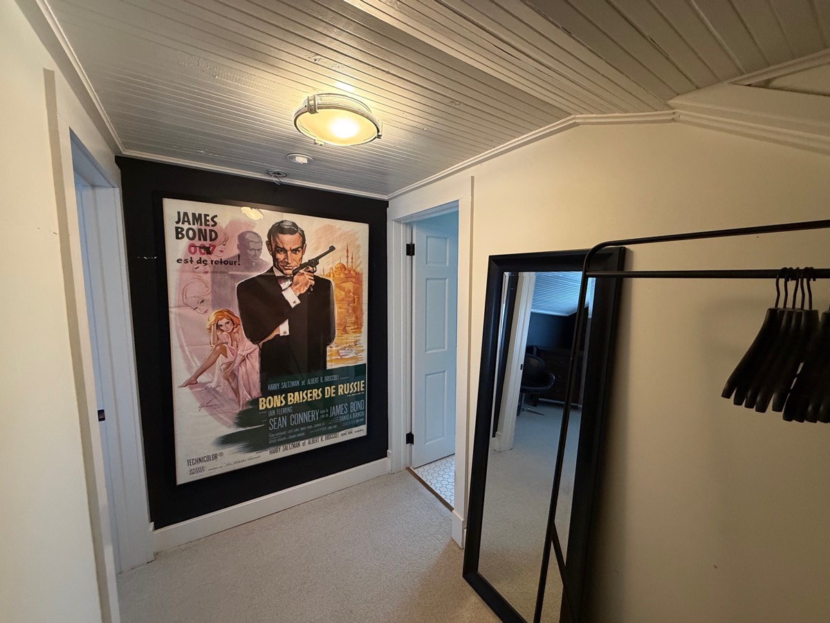 Upstairs hallway with a vintage French film poster and a floor mirror